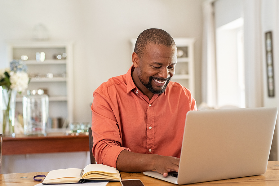 man sitting in front of computer smiling knowing his website is backed up and secure